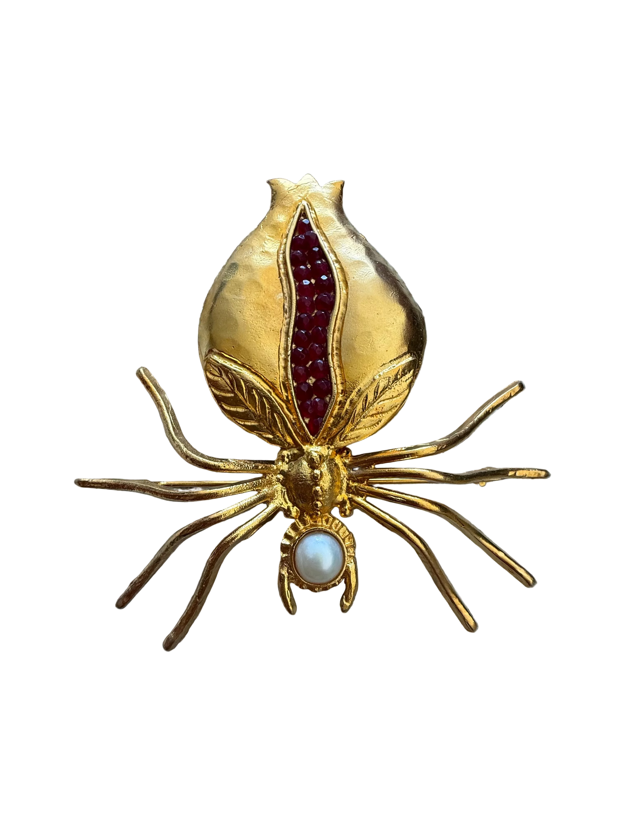 Gold spider-shaped brooch with red and pearl accents on a textured fabric background