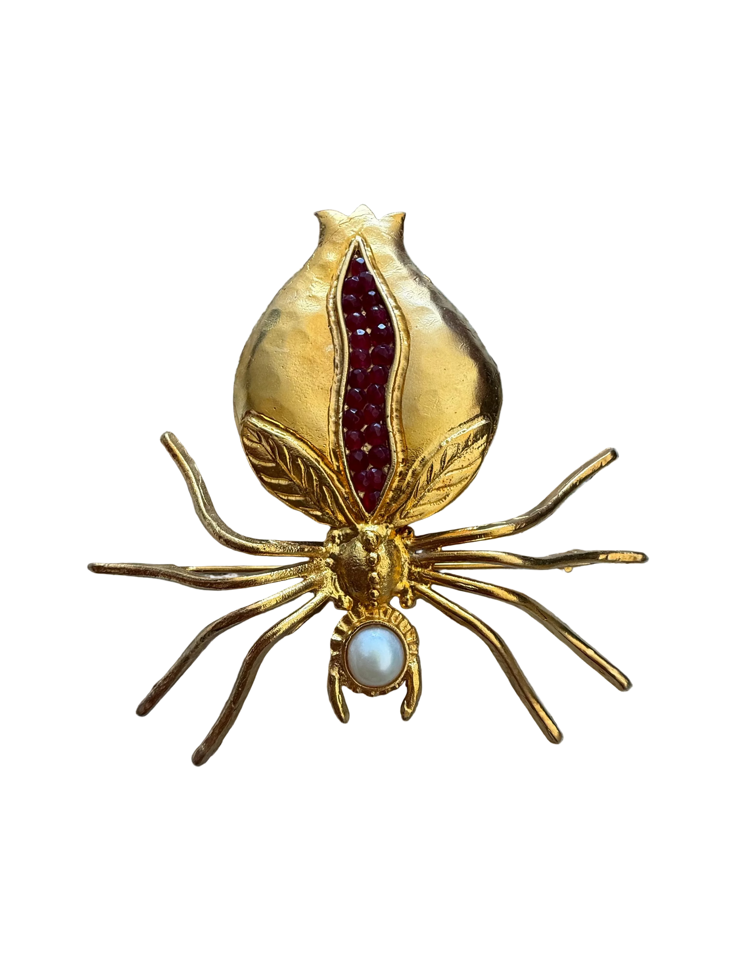 Gold spider-shaped brooch with red and pearl accents on a textured fabric background